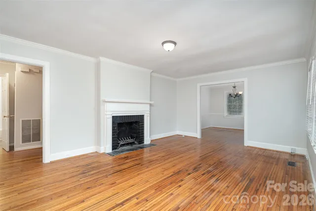 an empty room with wooden floor fireplace and windows