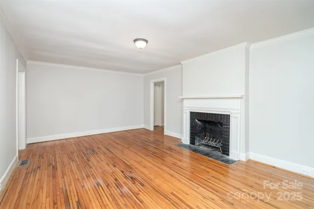 a view of empty room with wooden floor and fireplace