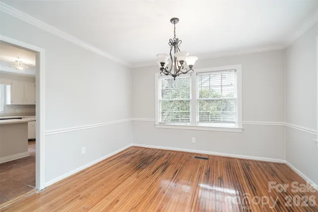 a view of empty room with wooden floor and chandelier