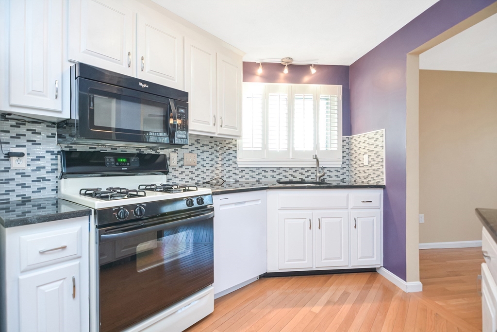 90 Mountain Gate Road, Unit 90 Ashland, MA 01721 - Photo 7 of 29 a kitchen with granite countertop wooden cabinets stainless steel appliances and a wooden floor