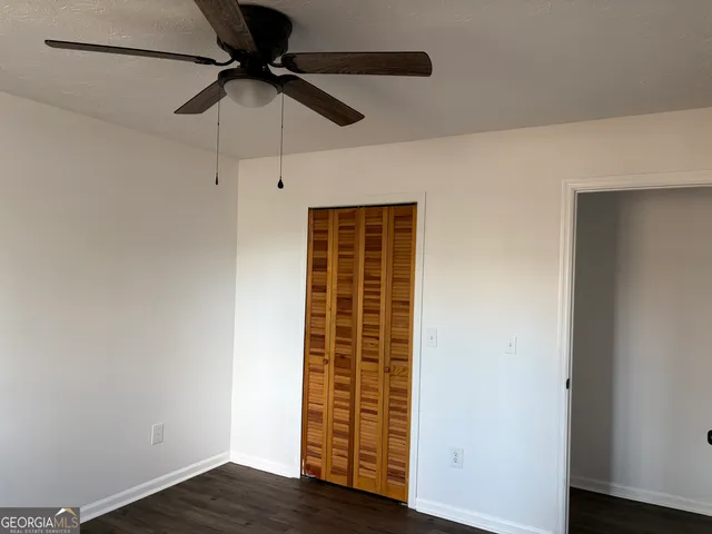 an empty room with wooden floor ceiling fan and window