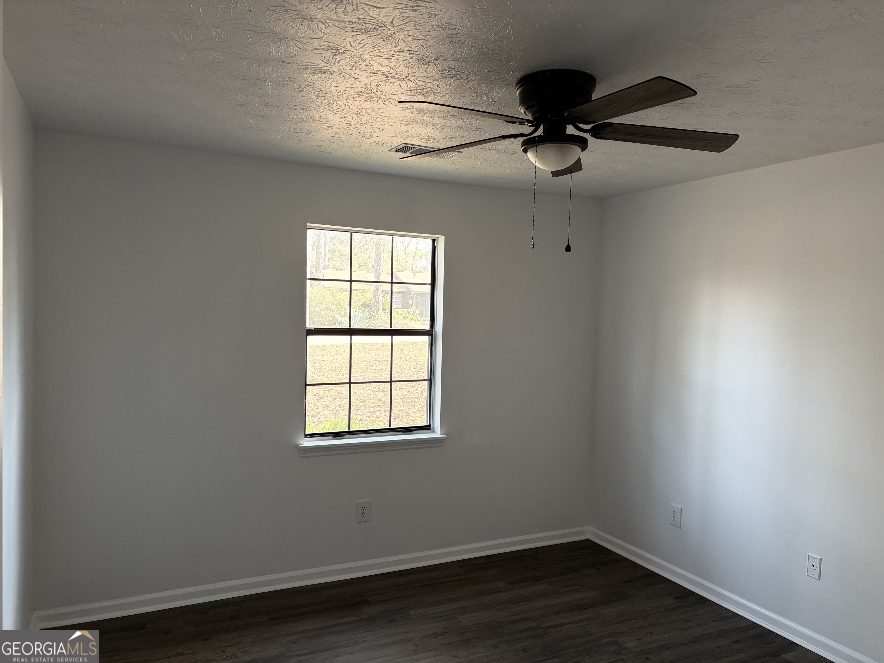 169 Ext N Jefferson Street Lyons, GA 30436 - Photo 17 of 18 an empty room with wooden floor ceiling fan and window