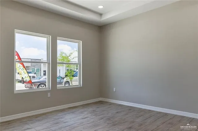 an empty room with wooden floor and windows