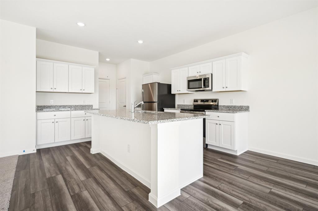 2403 States Street Princeton, TX 75407 - Photo 12 of 39 Kitchen with white cabinetry, light stone counters, appliances with stainless steel finishes, recessed lighting, and an island with sink