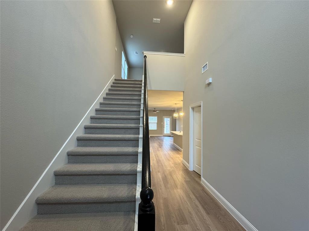 2403 States Street Princeton, TX 75407 - Photo 32 of 39 Stairway featuring wood finished floors, a towering ceiling, and a chandelier