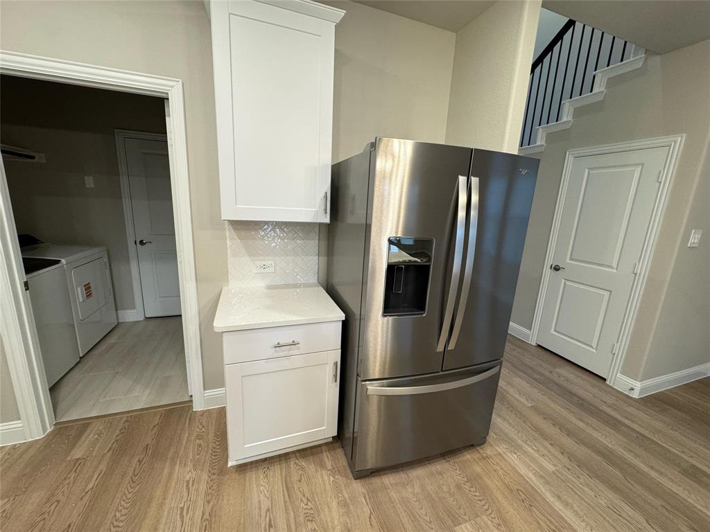 2403 States Street Princeton, TX 75407 - Photo 36 of 39 Kitchen featuring stainless steel fridge, white cabinetry, and light wood finished floors