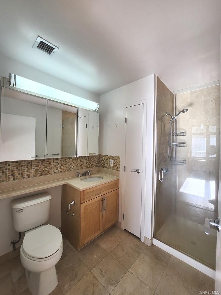 40-26 College Point Boulevard, Unit 18K Queens, NY 11354 - Photo 6 of 16 a bathroom with a granite countertop toilet a sink and a mirror