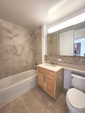 a bathroom with a granite countertop toilet sink and mirror