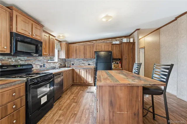 a kitchen with stainless steel appliances granite countertop a refrigerator a stove top oven a sink dishwasher and wooden cabinets with wooden floor