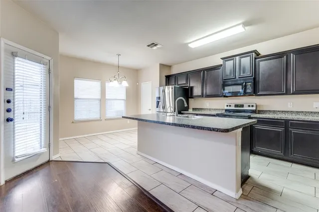 a kitchen with granite countertop wooden floors appliances and cabinets