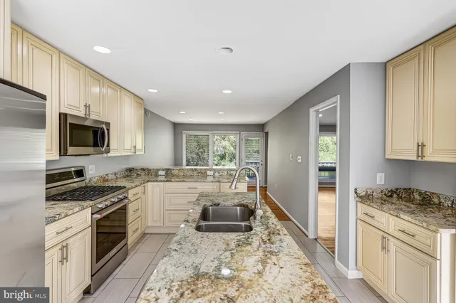 a kitchen with stainless steel appliances granite countertop a stove top oven a sink dishwasher a refrigerator and white cabinets with wooden floor