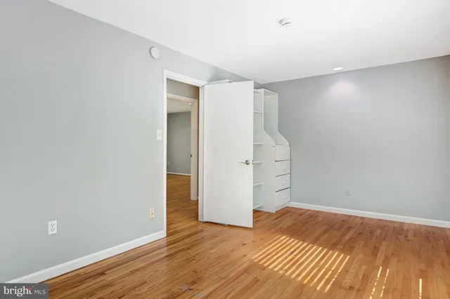 a view of an empty room with wooden floor and closet