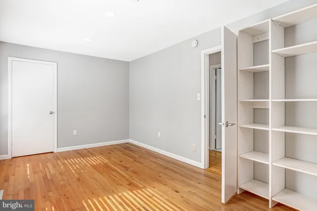 a view of an empty room with wooden floor and closet