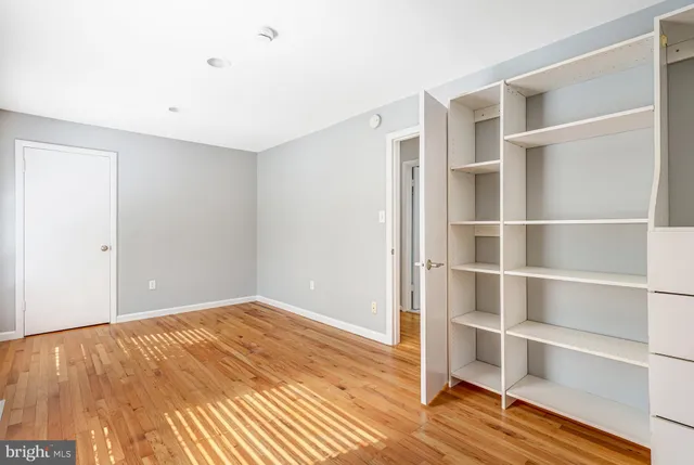 a view of an empty room with wooden floor and closet
