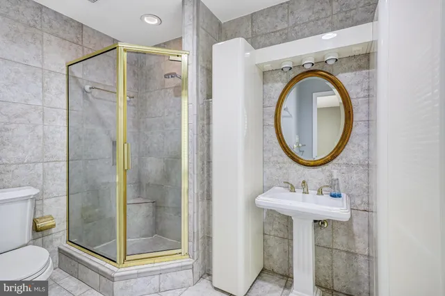 a bathroom with a sink a mirror a toilet and a glass door