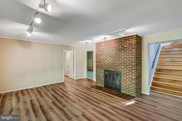 an empty room with wooden floor fireplace and windows
