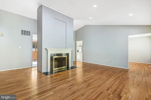 a view of an empty room with wooden floor fireplace and a window