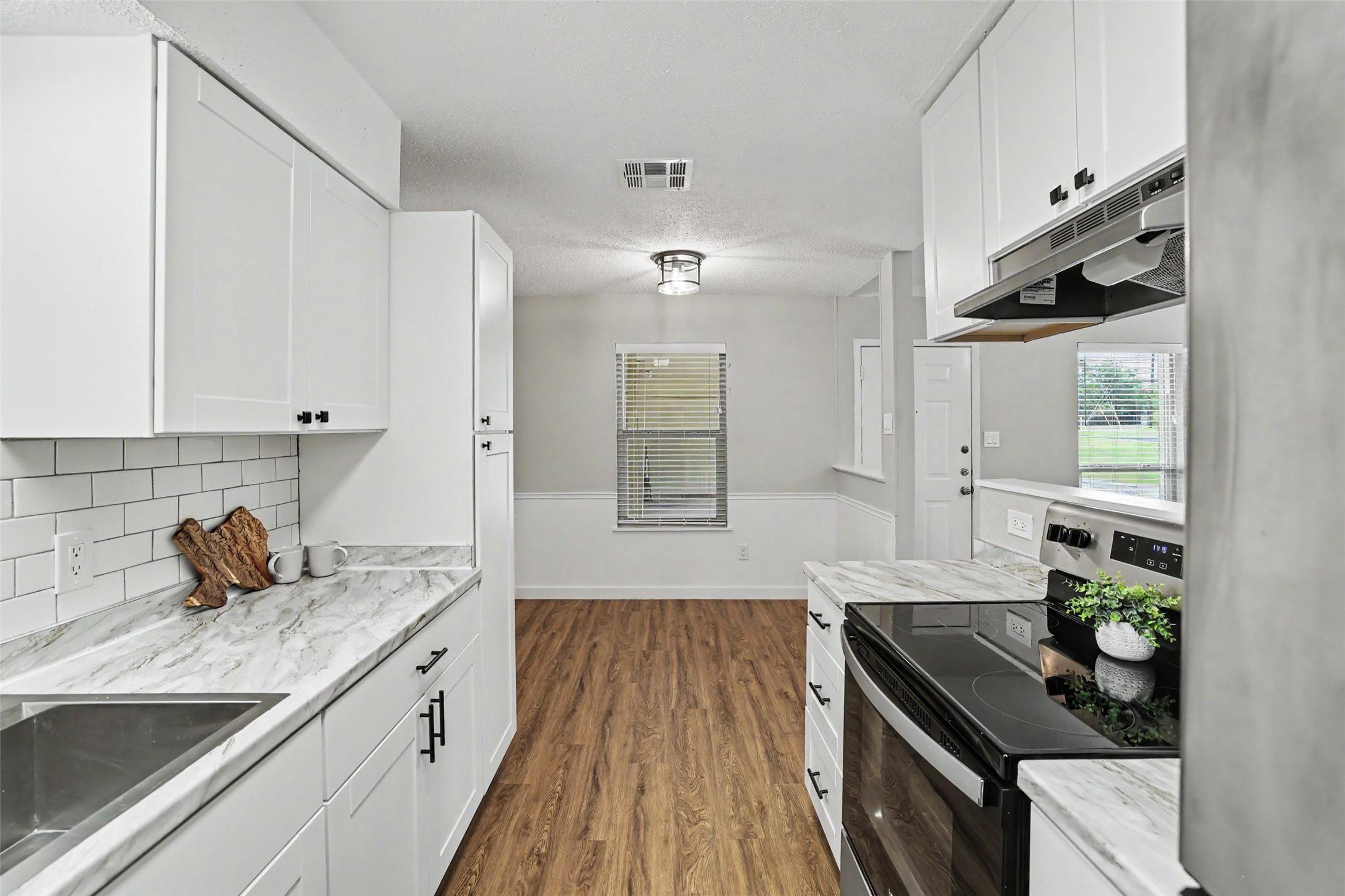 A galley kitchen with modern finishes flows into a bright dining space.