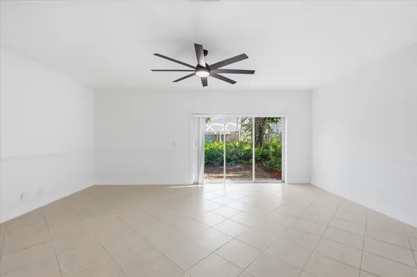 an empty room with chandelier fan and windows