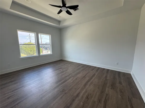 an empty room with wooden floor fan and windows