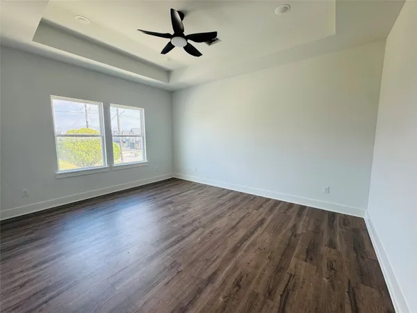 an empty room with wooden floor ceiling fan and windows
