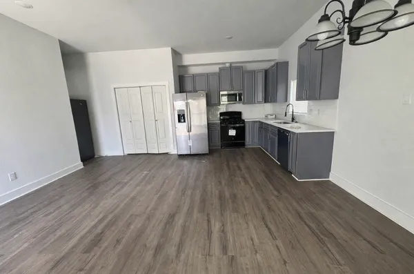 a large kitchen with a wooden floor and stainless steel appliances
