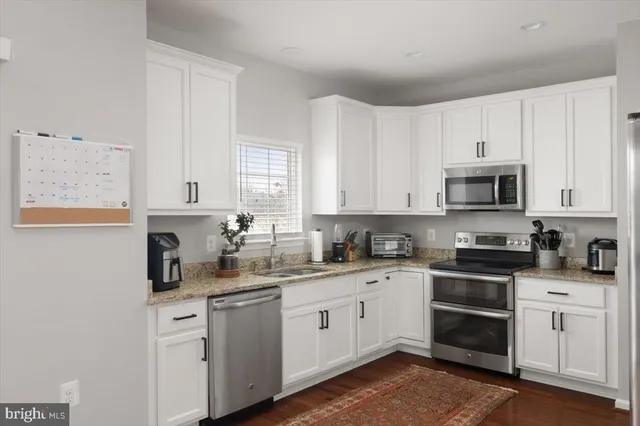 a kitchen with white cabinets stainless steel appliances and sink
