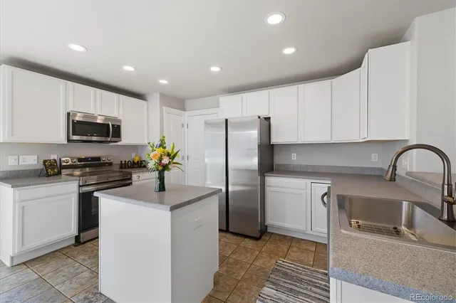 a kitchen with a refrigerator sink and white cabinets