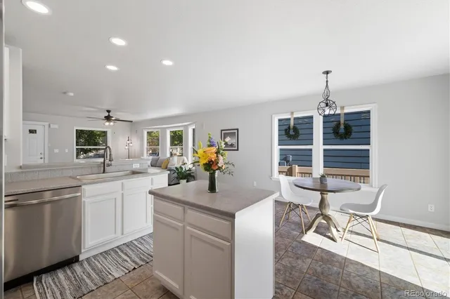 a kitchen with kitchen island a dining table chairs sink and cabinets