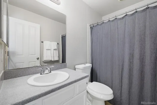 a bathroom with a sink a toilet a mirror and shower curtain