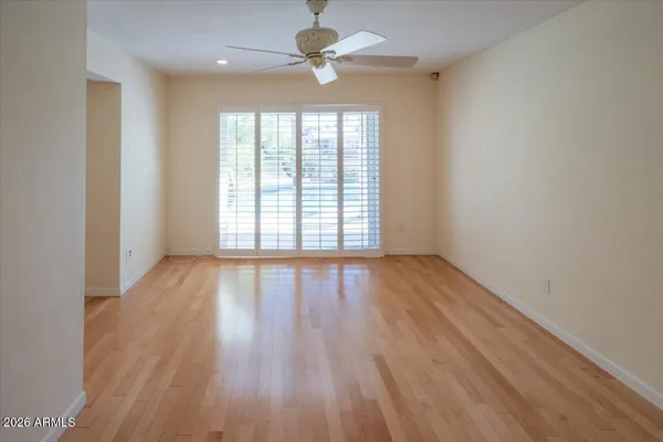 an empty room with wooden floor fan and windows