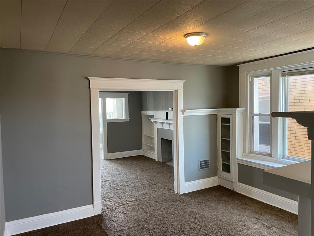 732 Bay Ridge Avenue, Unit 2 Brookline, PA 15226 - Photo 3 of 9 an empty room with a fireplace and windows