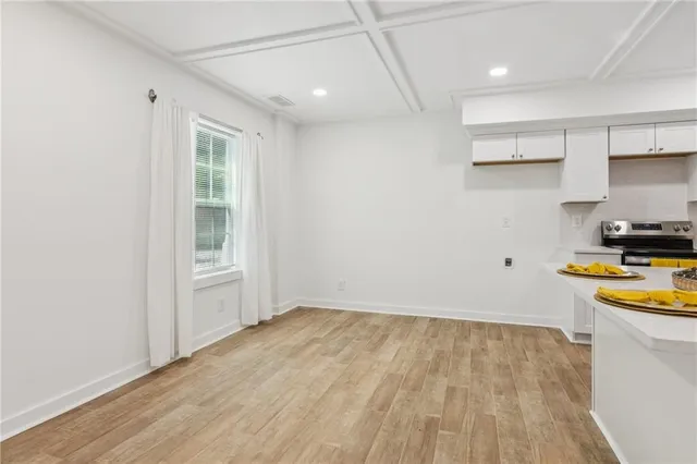 a view of hallway with window and wooden floor