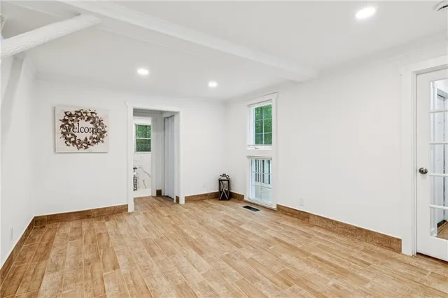 an empty room with wooden floor and windows