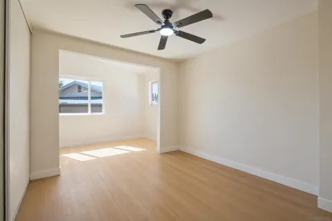 an empty room with a window and a ceiling fan