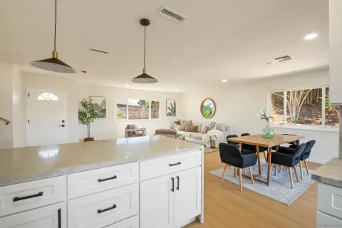 a kitchen with stainless steel appliances granite countertop a stove a sink a dining table and chairs with wooden floor