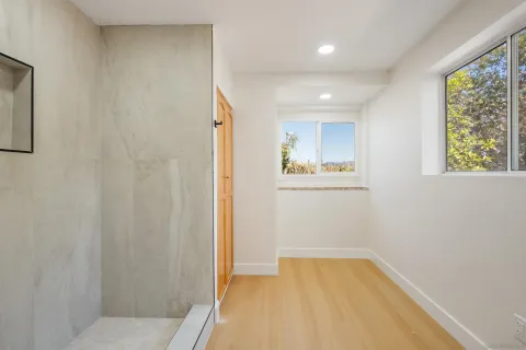 a view of empty room with wooden floor and fan
