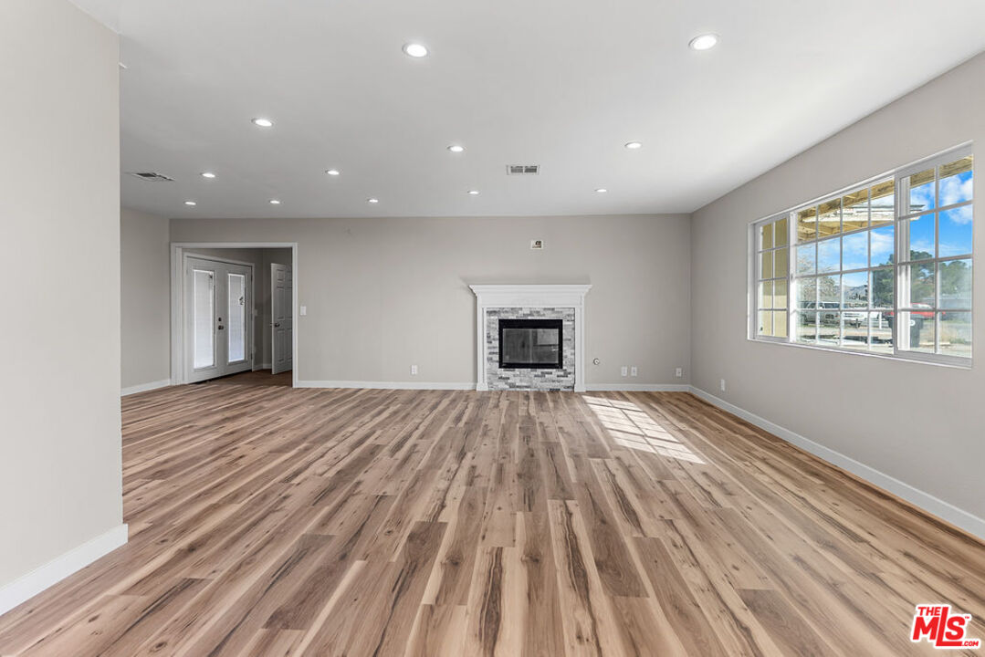 16030 Osage Road Apple Valley, CA 92307 - Photo 26 of 27 an empty room with wooden floor a fireplace and windows