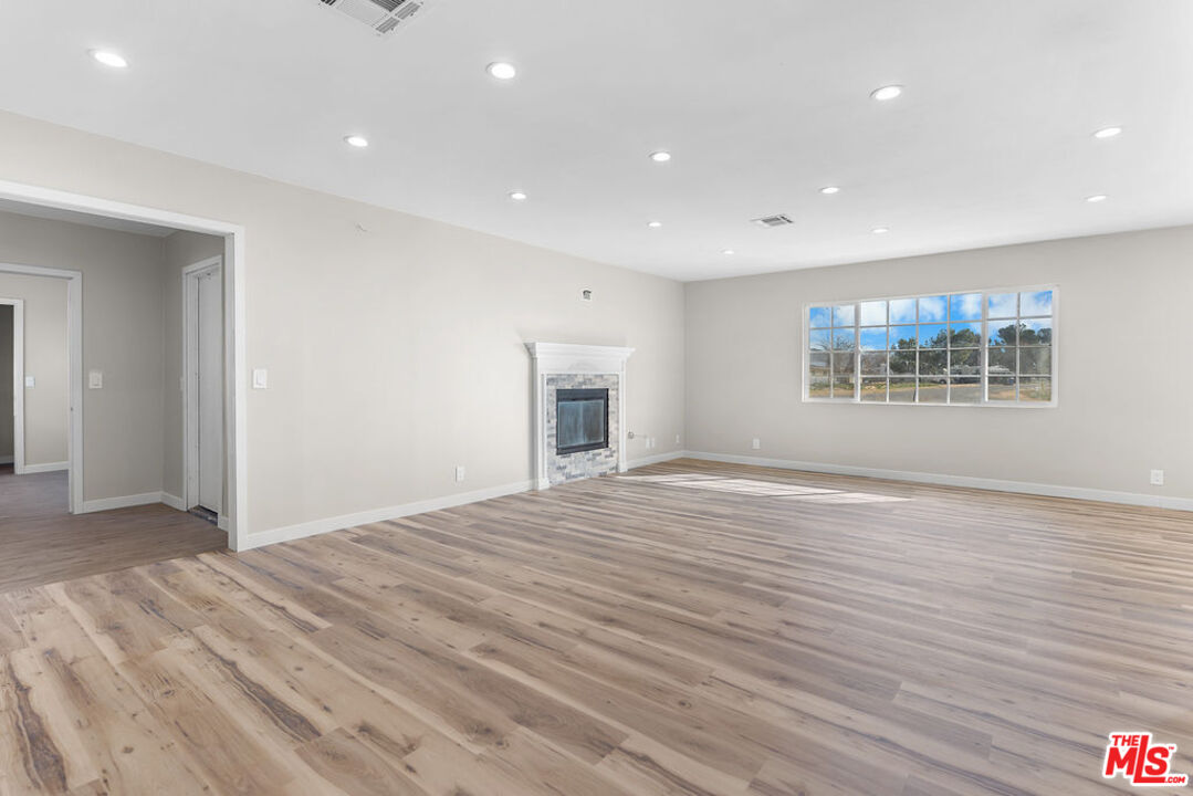 16030 Osage Road Apple Valley, CA 92307 - Photo 7 of 27 an empty room with wooden floor and a fireplace