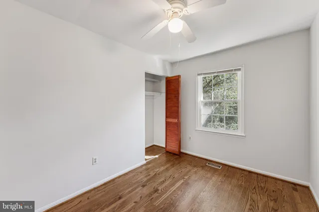 an empty room with wooden floor fireplace and windows