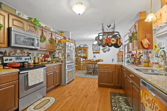 a kitchen with stainless steel appliances granite countertop a stove a sink dishwasher and cabinets with wooden floor