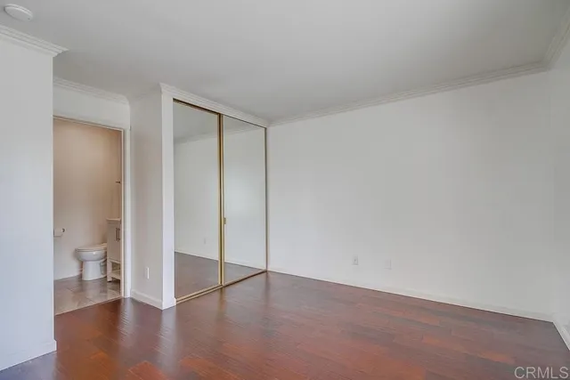 an empty room with wooden floor and a toilet