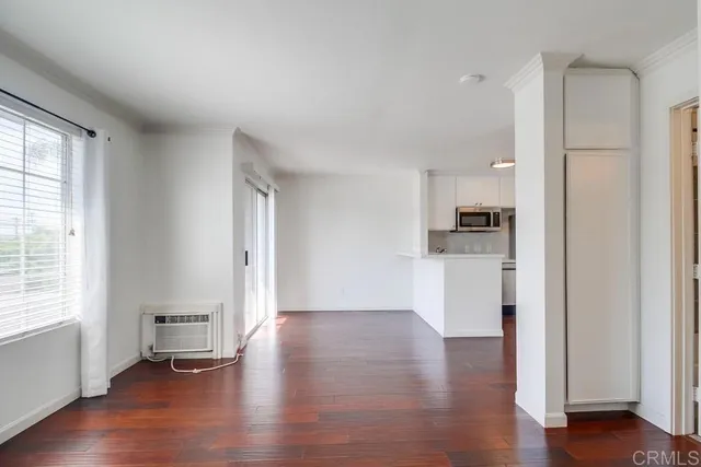 a view of empty room with wooden floor and window
