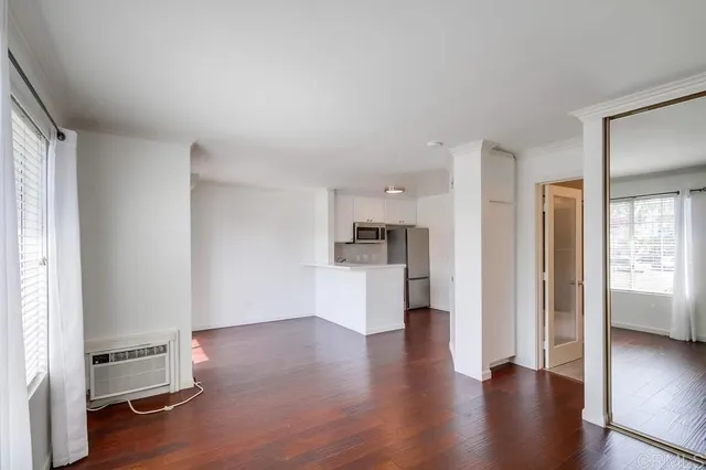 a view of an empty room and kitchen with a sink oven window