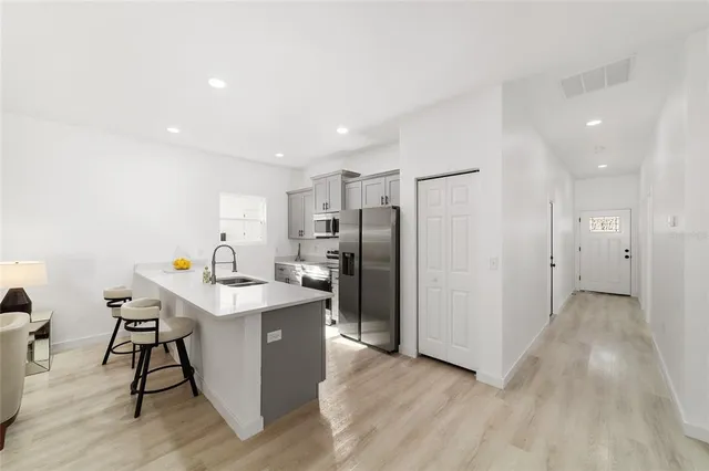 a kitchen with stainless steel appliances a refrigerator a sink a stove a dining table and chairs