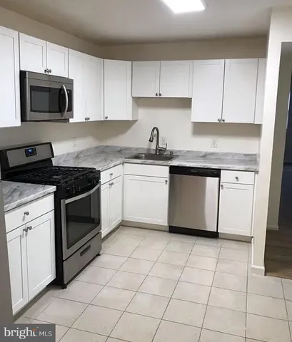 a kitchen with cabinets stainless steel appliances a sink and a counter space