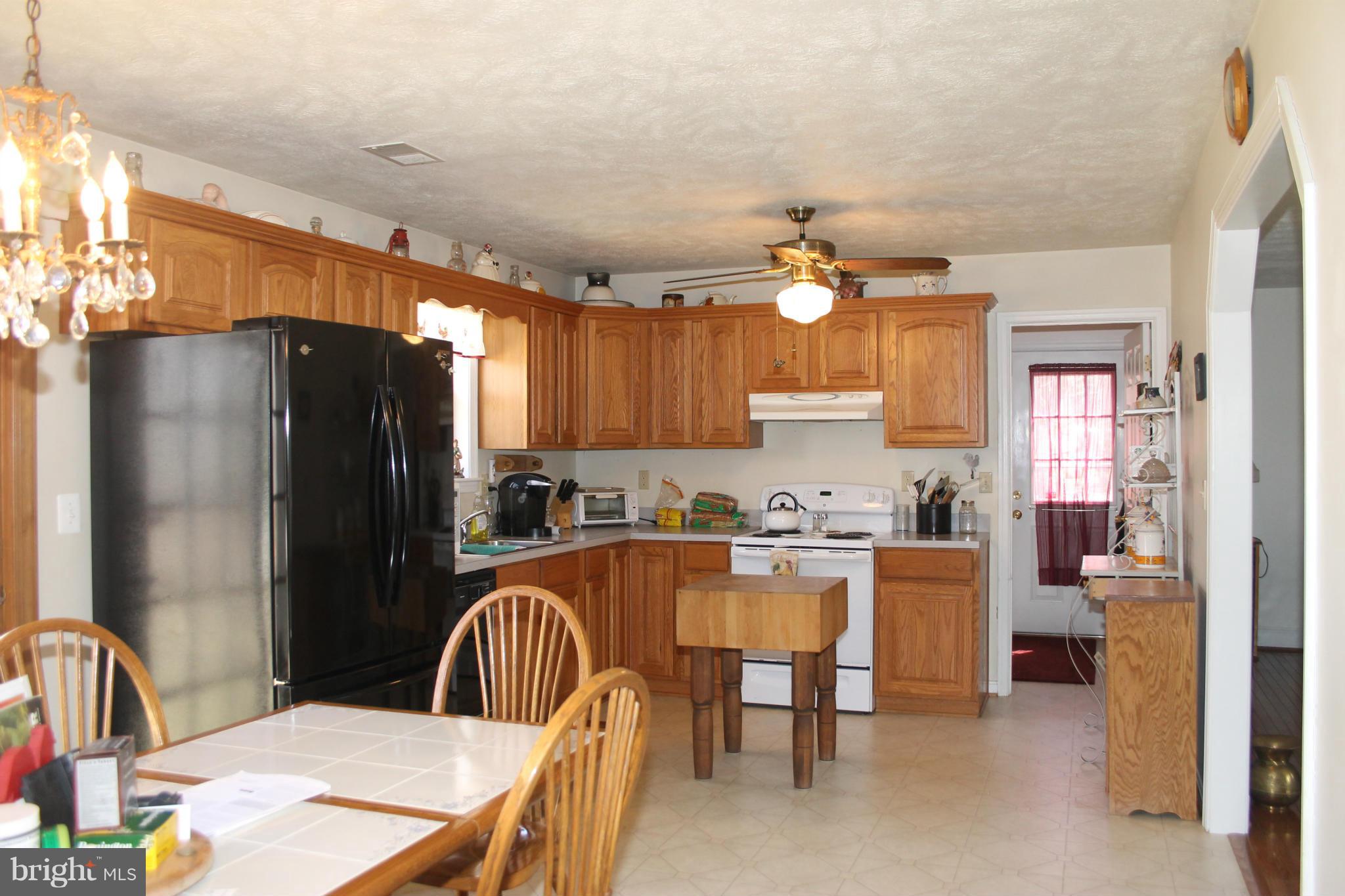 10275 Dutch Hollow Road Rixeyville, VA 22737 - Photo 6 of 21 a kitchen with granite countertop a dining table chairs refrigerator and cabinets