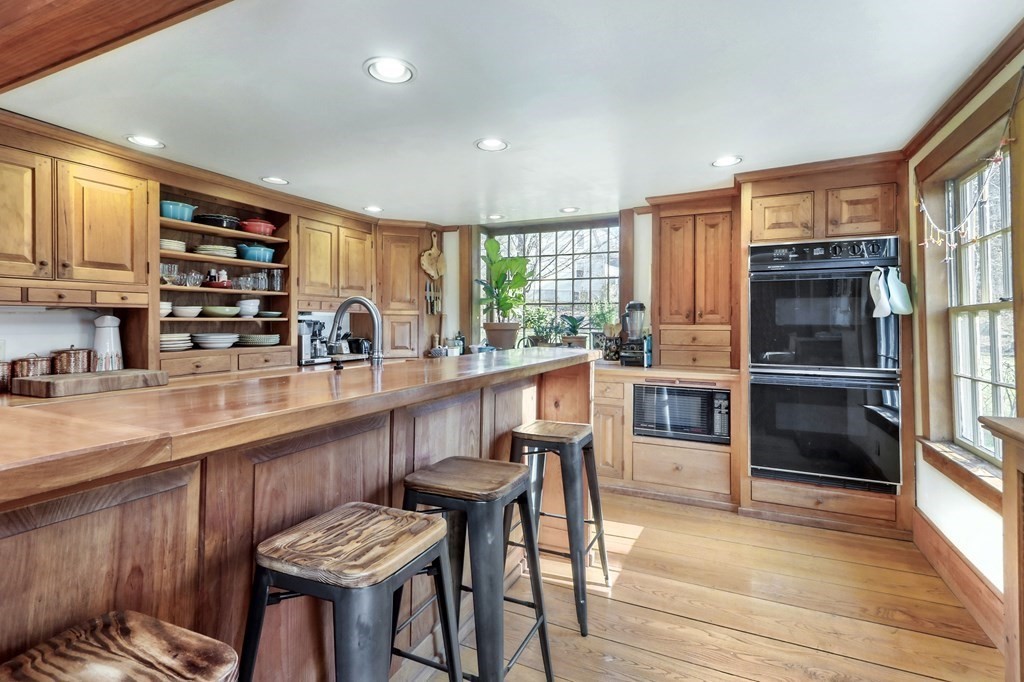 150 Concord Road Sudbury, MA 01776 - Photo 8 of 34 a kitchen with stainless steel appliances kitchen island granite countertop a table chairs in it and a wooden floors