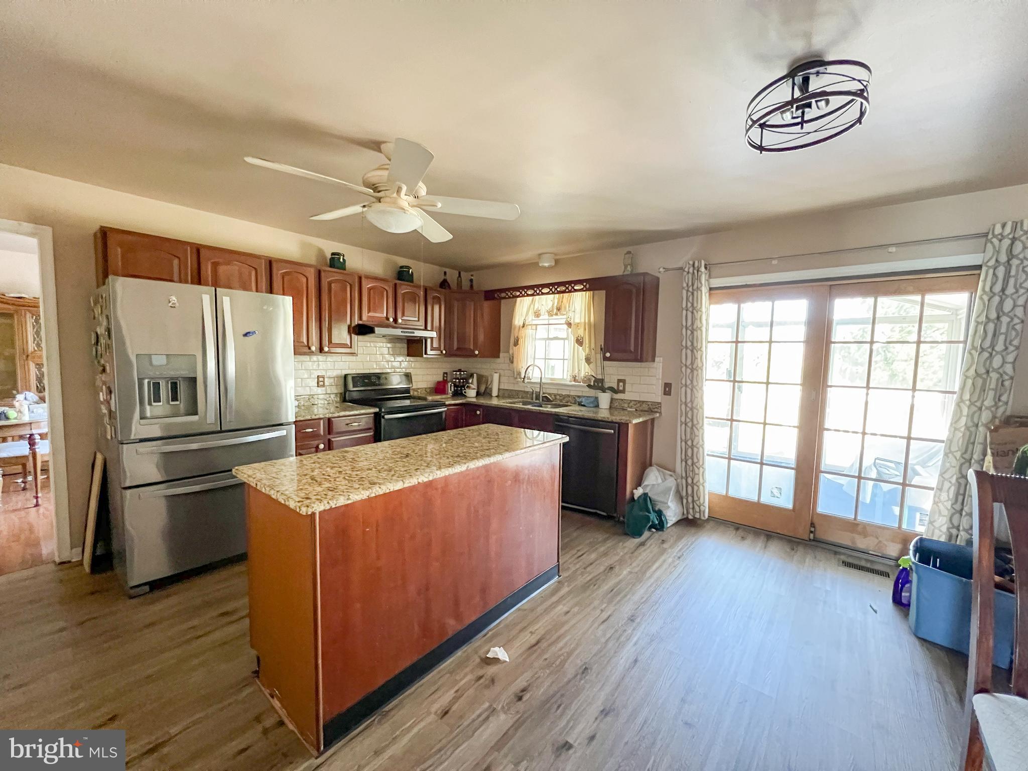 214 Mt Vernon Drive Bear, DE 19701 - Photo 8 of 44 a kitchen with stainless steel appliances a refrigerator a sink dishwasher a stove and a dining table with wooden floor