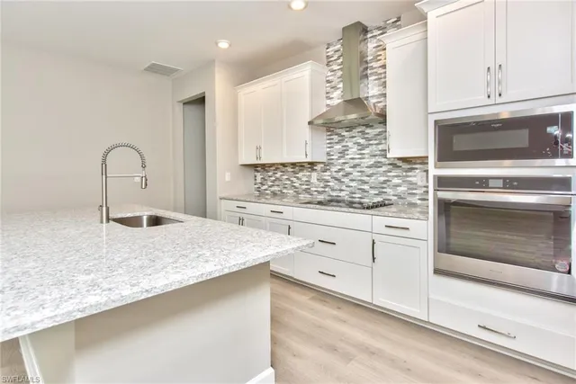 a kitchen with white cabinets and sink